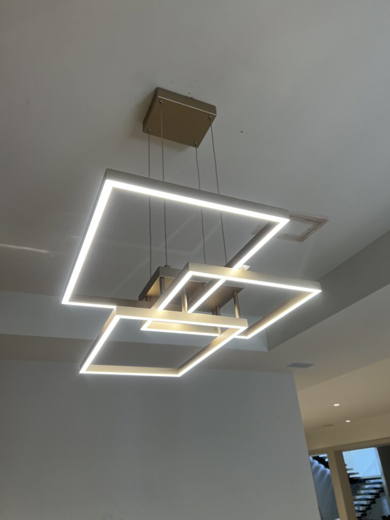 A modern geometric LED ceiling light fixture with overlapping square frames, suspended from a rectangular base.