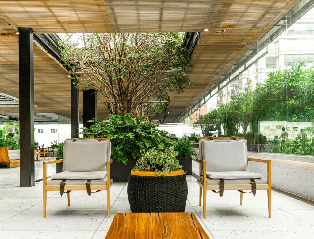 Two wooden chairs with cushions face a wooden table on a modern patio, enhanced by strategic landscape lighting design.