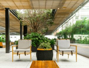 Two wooden chairs with cushions face a wooden table on a modern patio, enhanced by strategic landscape lighting design.