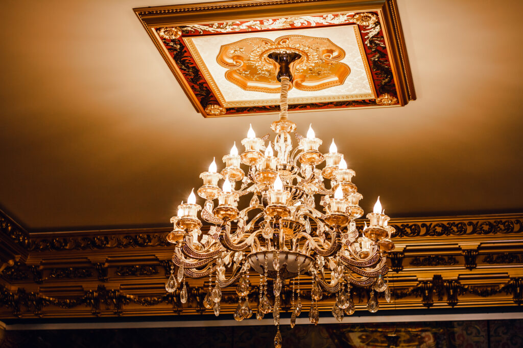 An elegant chandelier, the epitome of custom lighting design, hangs from an ornate ceiling