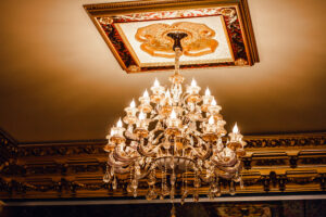 An elegant chandelier, the epitome of custom lighting design, hangs from an ornate ceiling