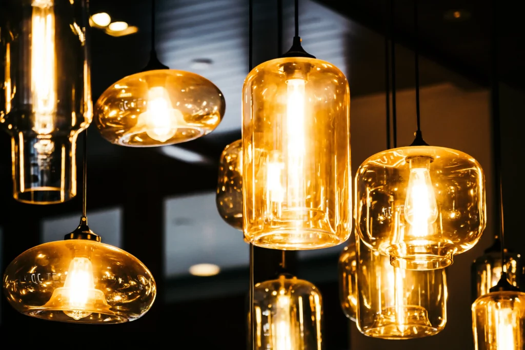 Professional Lighting Design Services: Hidden Cost Savings Your Architect Won't Tell You 3 Multiple glass pendant lights with exposed bulbs hang from the ceiling, emitting a warm yellow glow in an indoor setting.